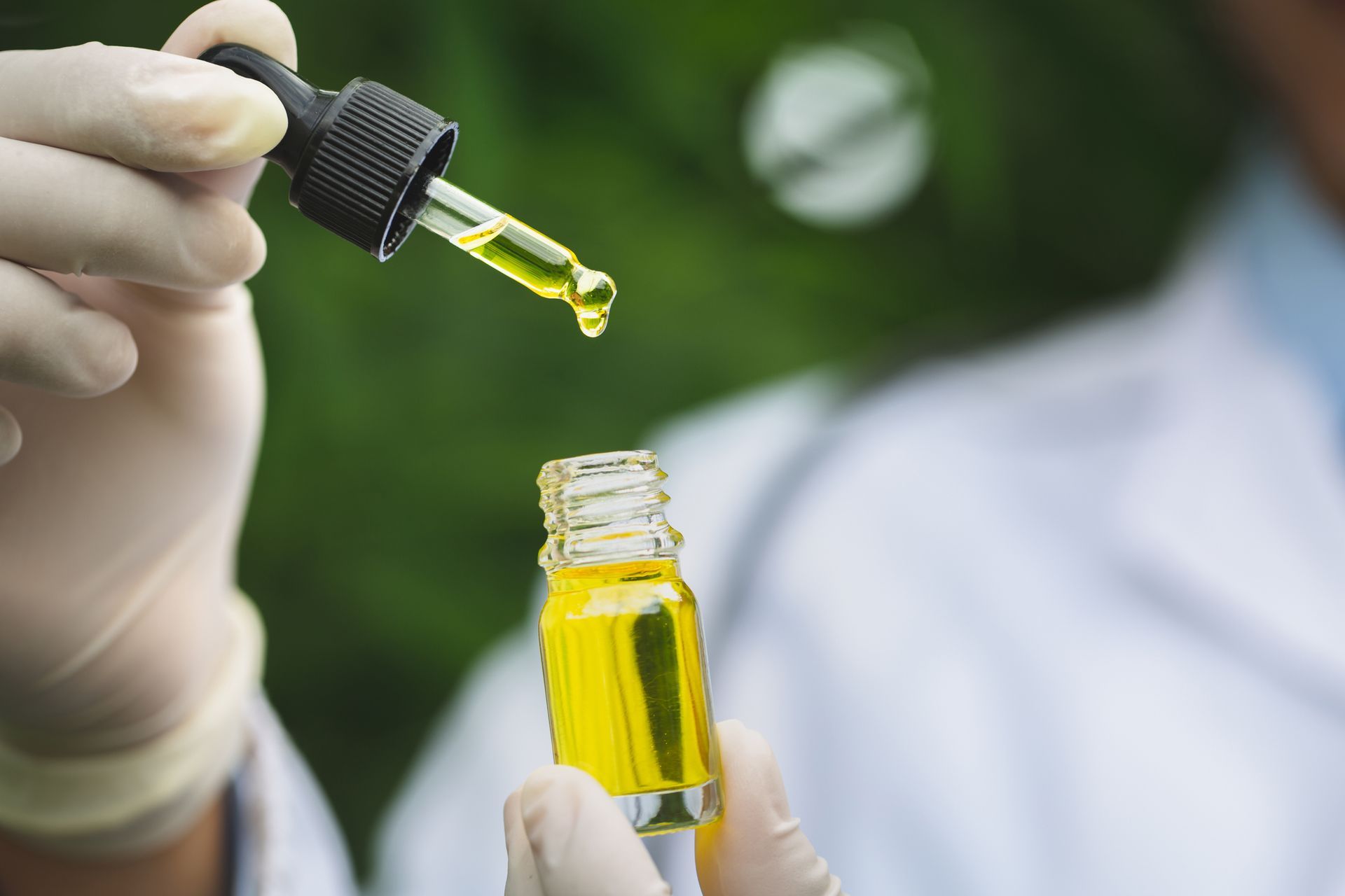 A person is holding a bottle of oil and a pipette. A person is holding a bottle of oil and a pipette.