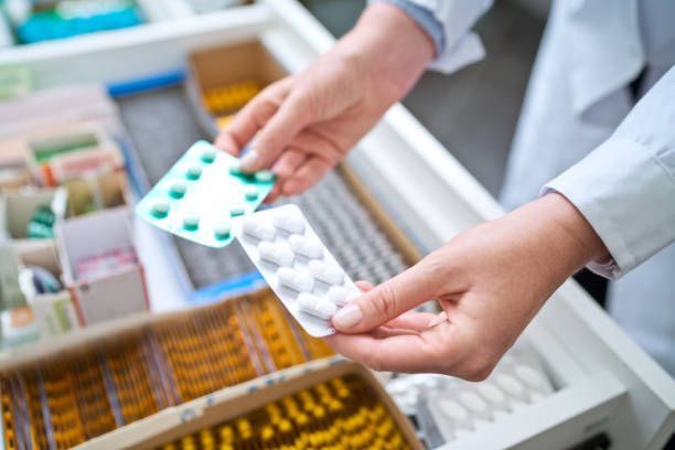 Female pharmacist holding pills above drawer with medicines at a compound medicine pharmacy.