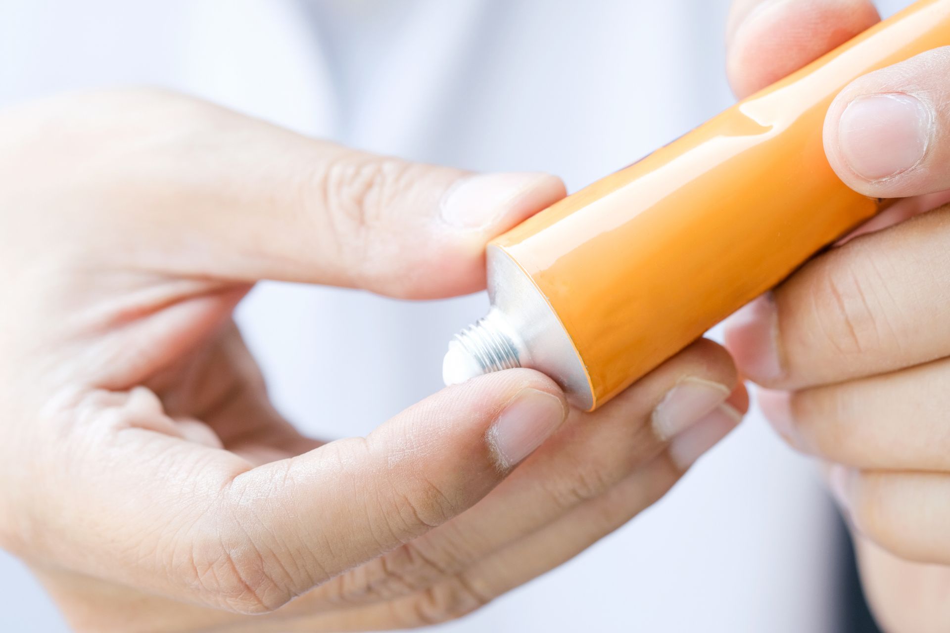A person is holding a tube of ointment in their hand.