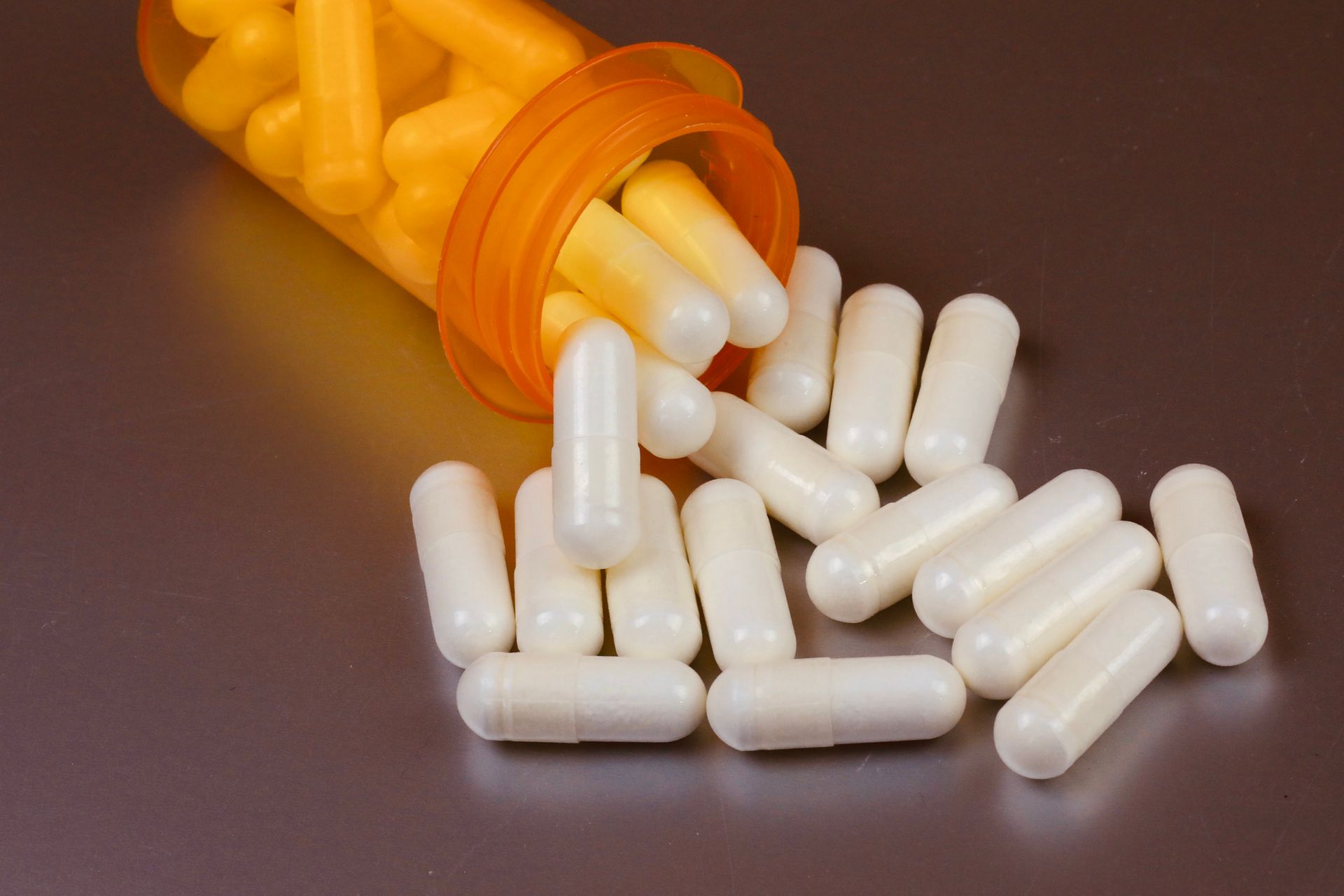 A bottle of pills is pouring out of it on a table
