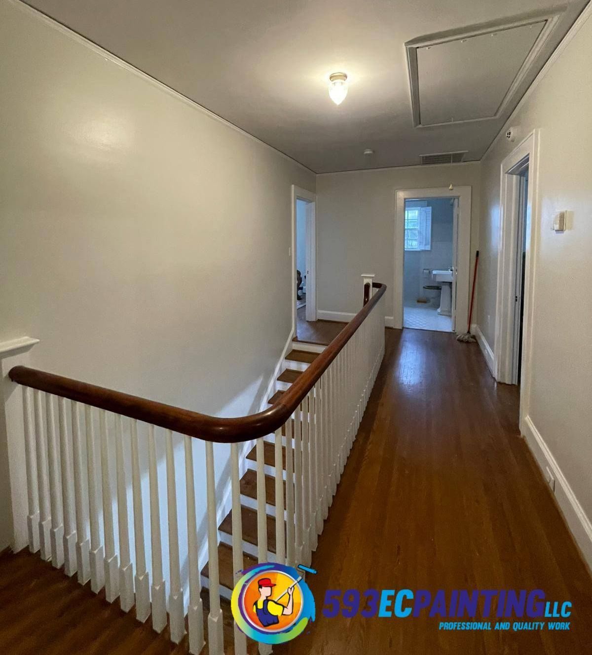 A hallway with stairs and a railing in a house.