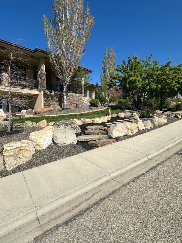 A large house is sitting on top of a hill next to a sidewalk.
