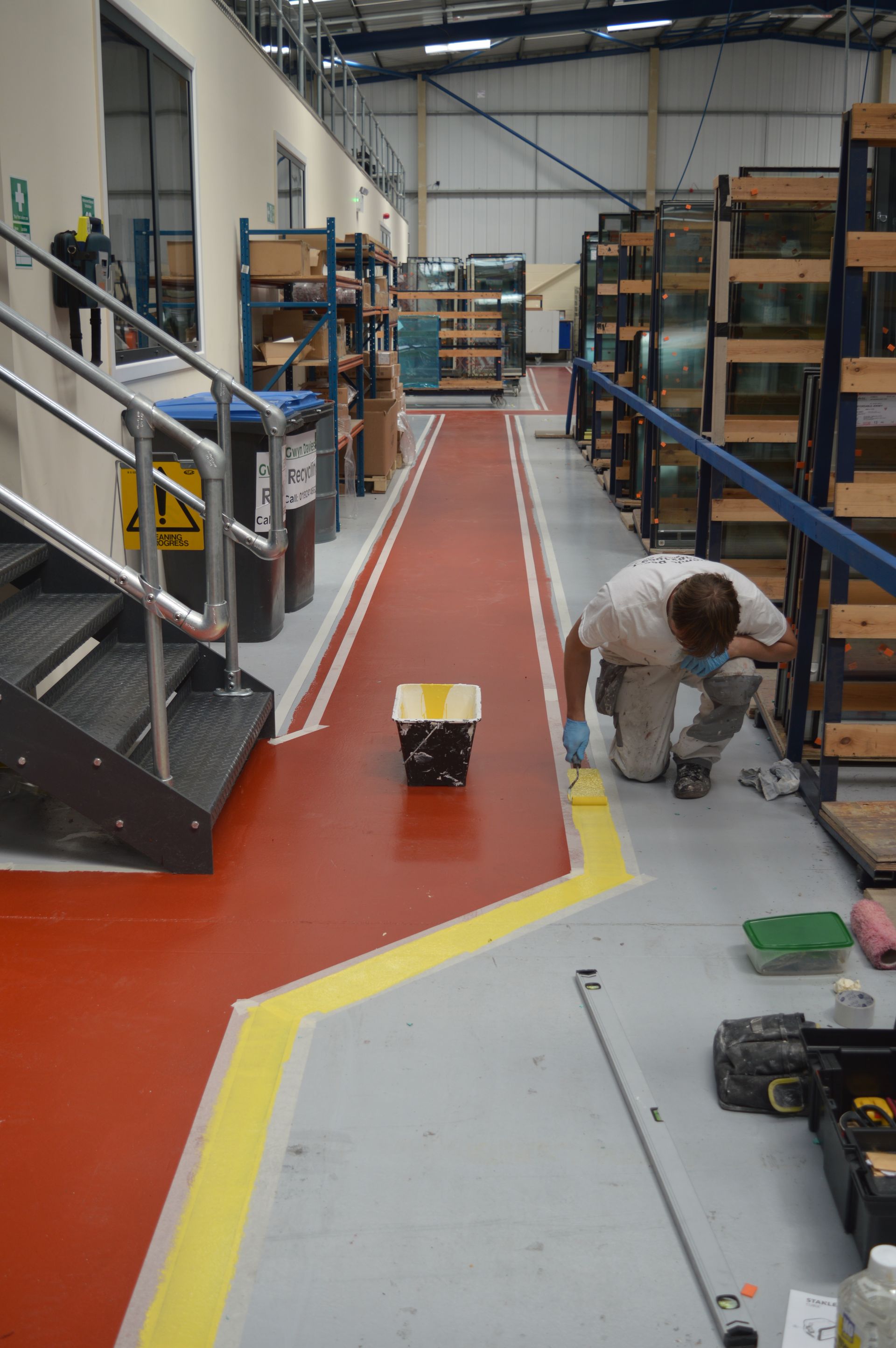 Out-of-hours floor marking maintenance – technician applying durable safety lines in operational warehouse