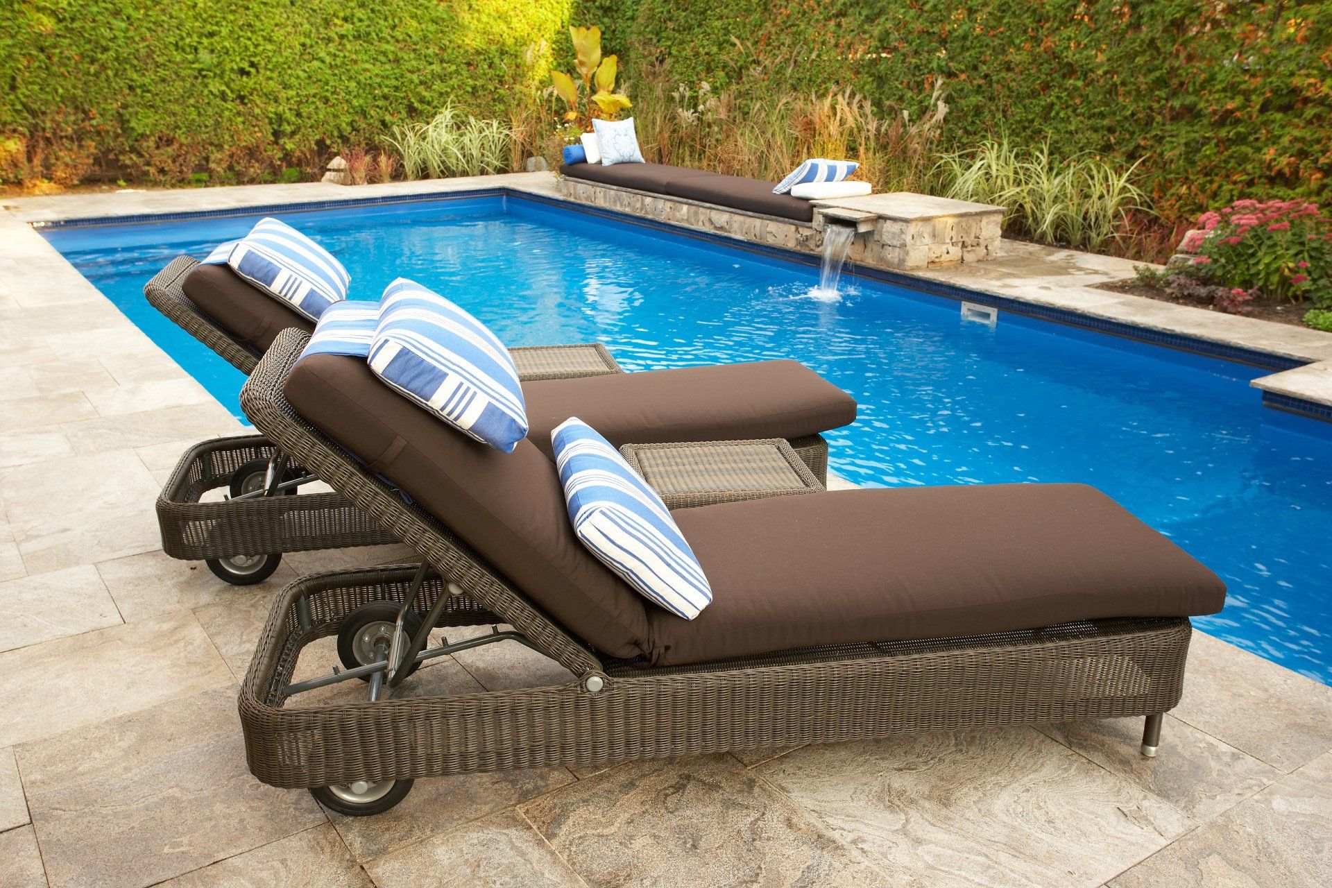 2 lounge chairs with pillows beside backyard swimming pool