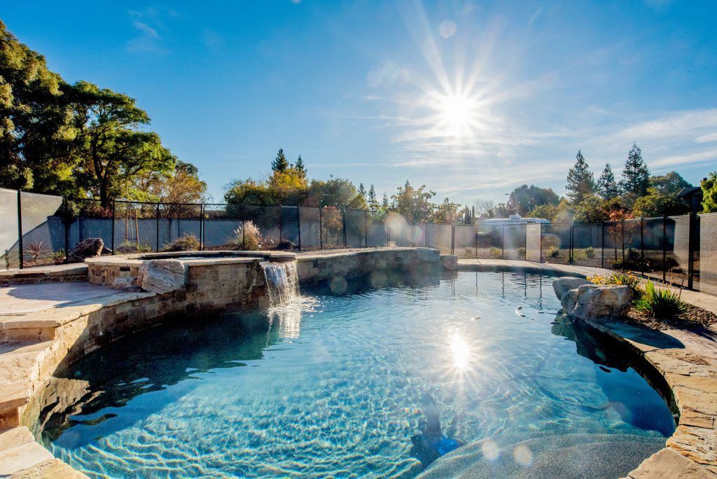 Photo of elegant pool in backyard with waterfall feature