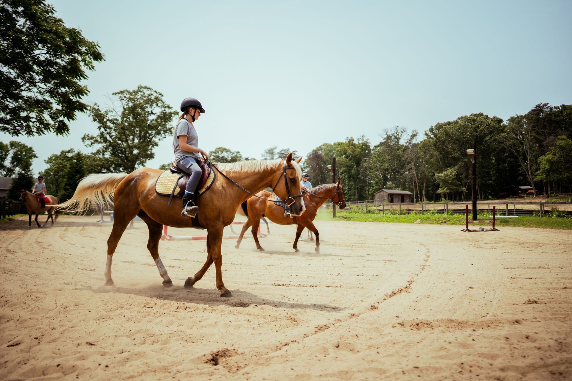 A woman is riding a horse in a dirt field.