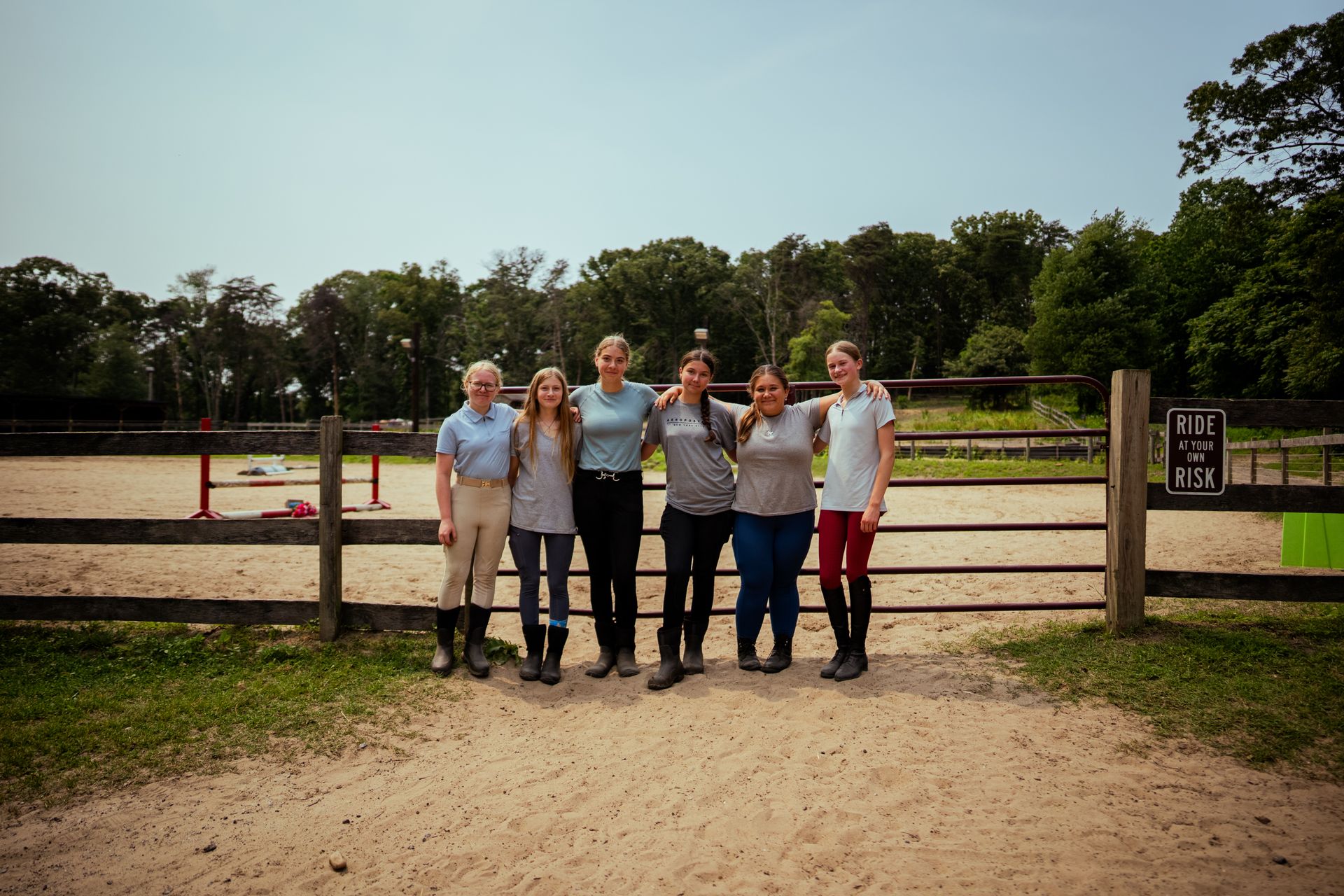 A group of young women are posing for a picture in front of a wooden fence.