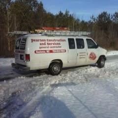 A white Pearson Construction and Services van with a roof ladder rack parked on a snowy, ice-covered road.