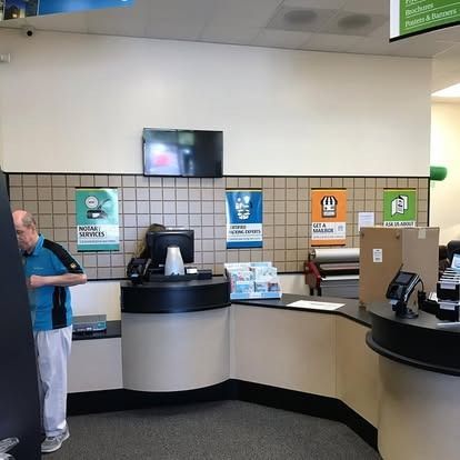 A service counter at a retail store, with a person standing behind it and colorful instructional signage on the wall.