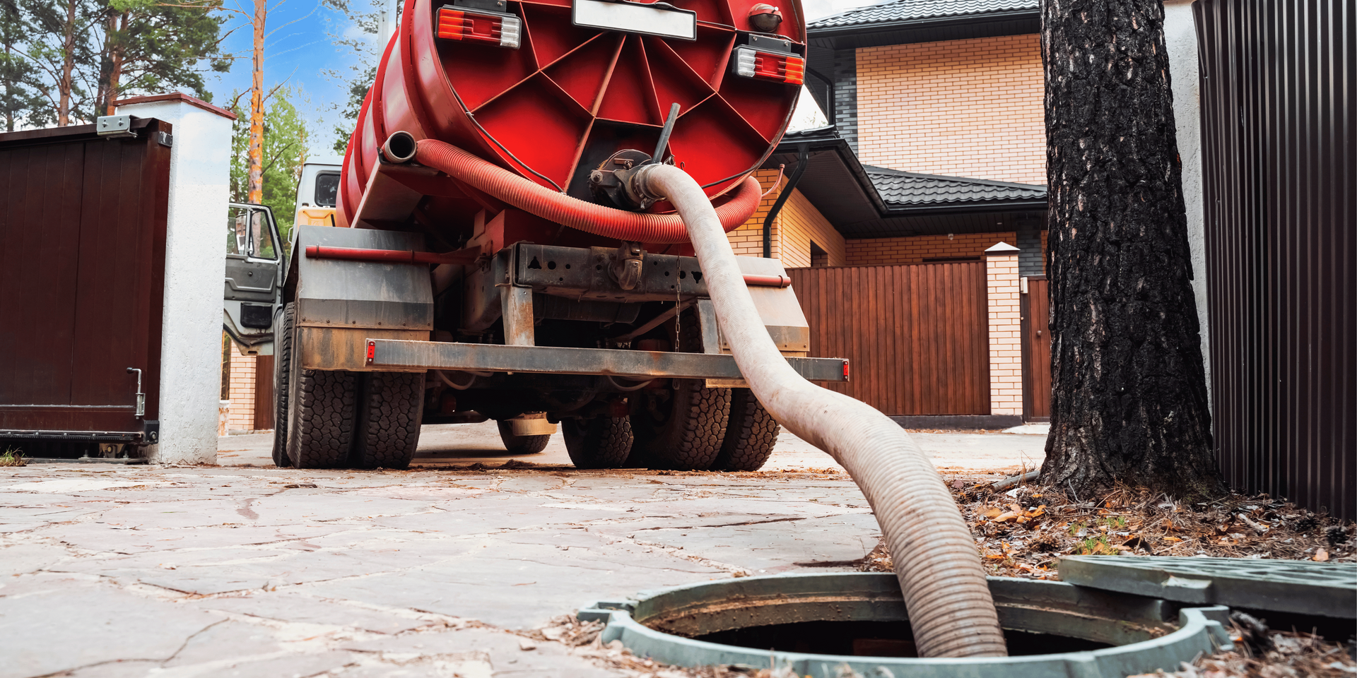 Rusty pipes running along a concrete basement ceiling, with a glimpse of a furnace and doorway.