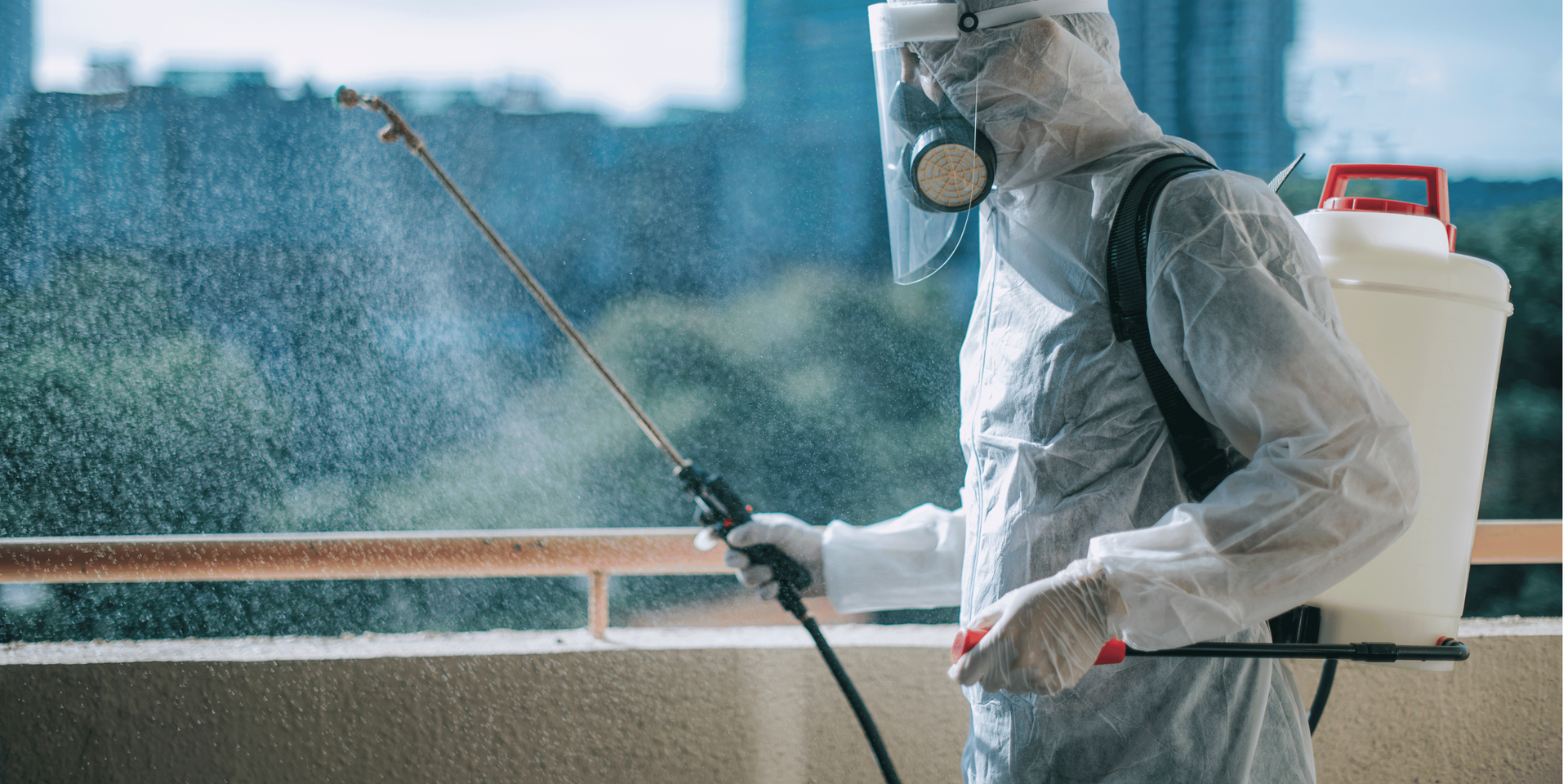 Man installing plastic sheeting on a ceiling in a room with arched windows and brickwork. He wears a red hoodie and jeans.