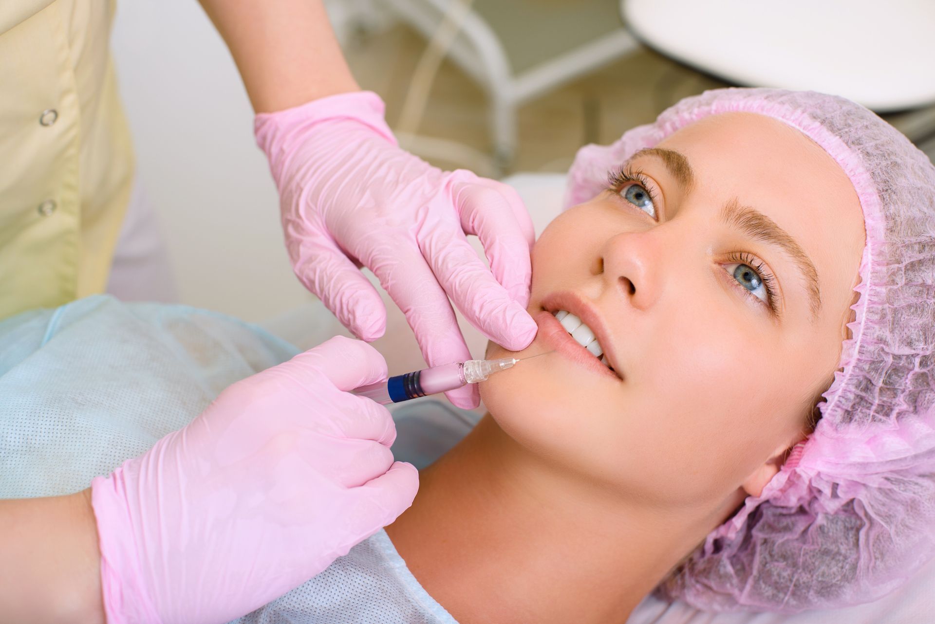 A woman is getting a botox injection in her lips.