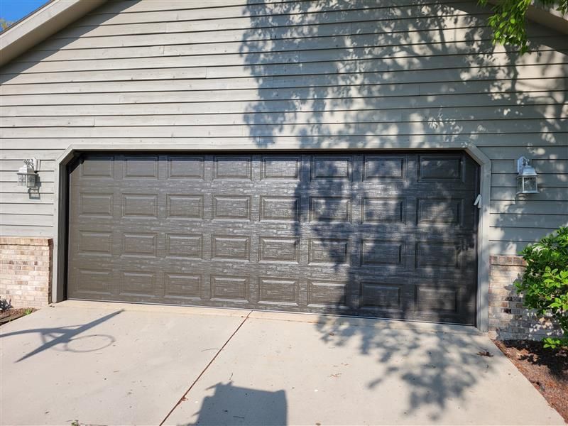 A white garage with a blue roof has a potted plant in front of it