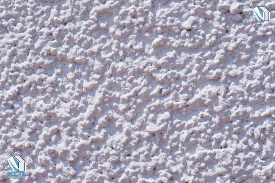 A close-up view of a white popcorn-textured ceiling, showing its rough and bumpy surface. The texture appears aged, with signs of wear that may require professional sheetrock repair. This image highlights the need for expert popcorn ceiling repair in 9011 Sandra Wy, Barling, AR 72923