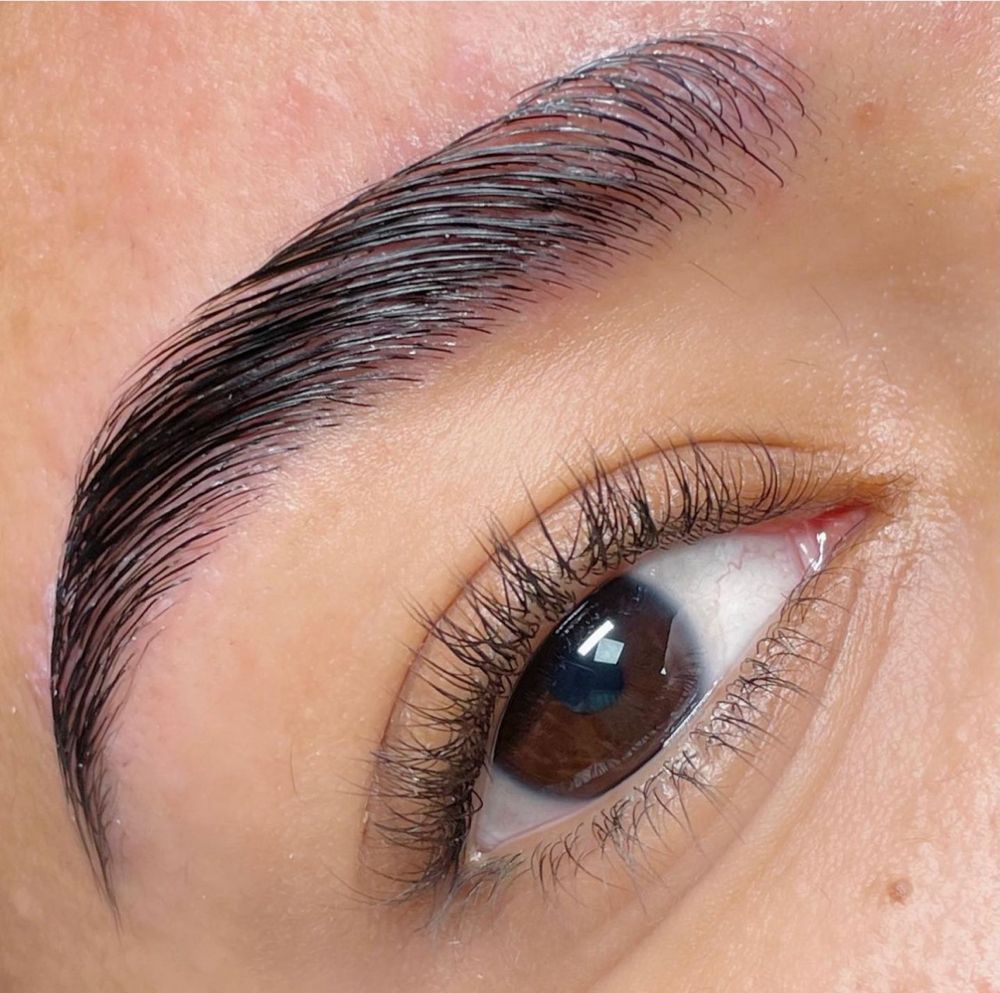 A close up of a woman 's eye with long eyelashes and a thick eyebrow.