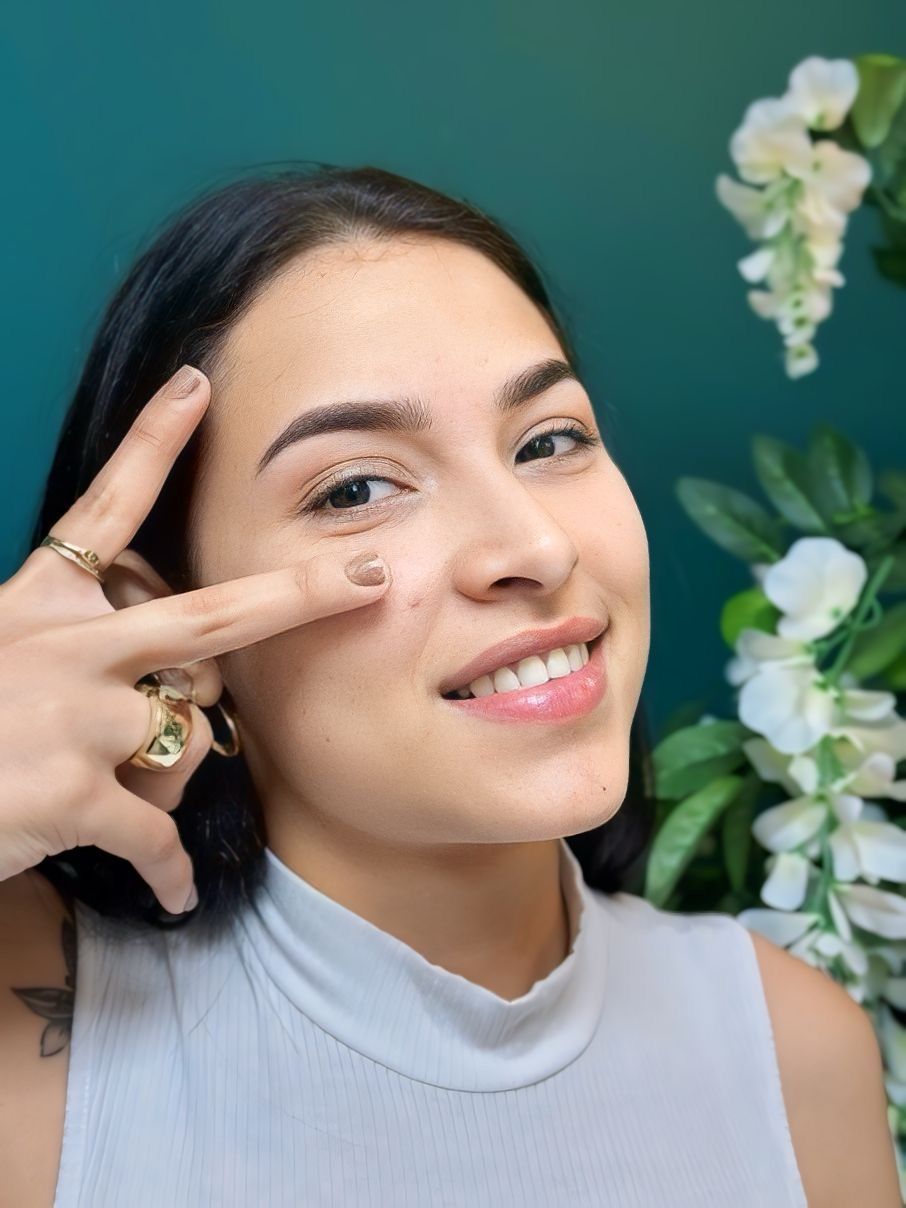 A woman with a ring on her finger is smiling and making a peace sign.