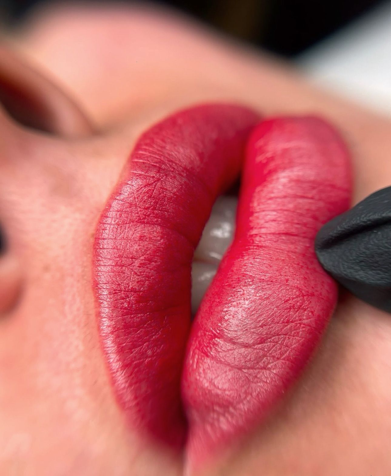 A close up of a woman 's lips with red lipstick being applied to them.