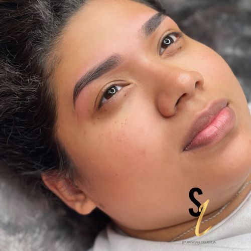 A close up of a woman 's face with a tattoo on her eyebrows.