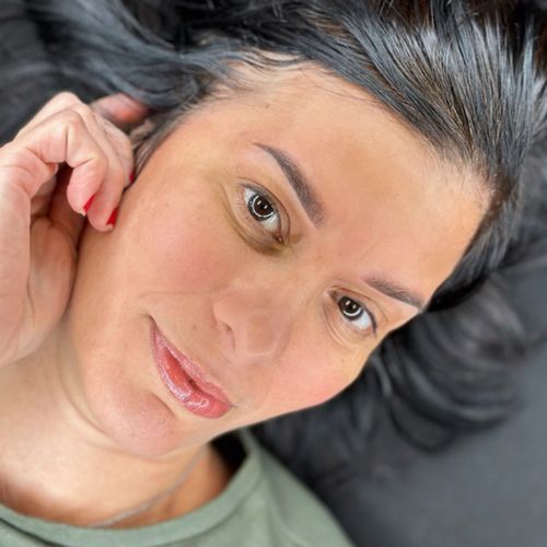 A close up of a woman 's face with her hand on her ear.