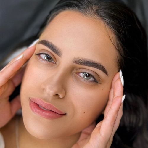 A close up of a woman 's face with her hands on her forehead