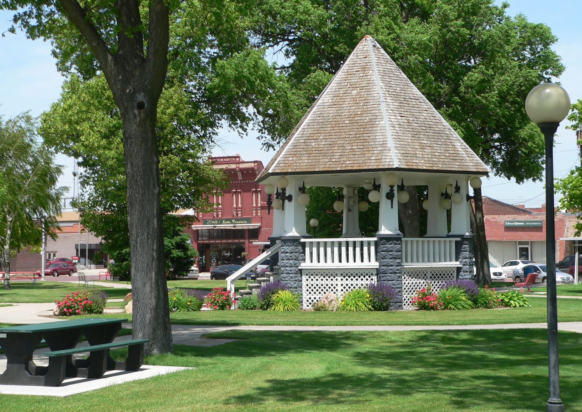 A gazebo in a park with a picnic table in front of it