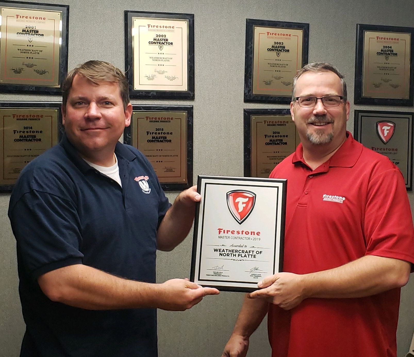 Two men are holding a certificate that says firestone