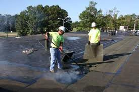 Two men are working on a roof with shovels.