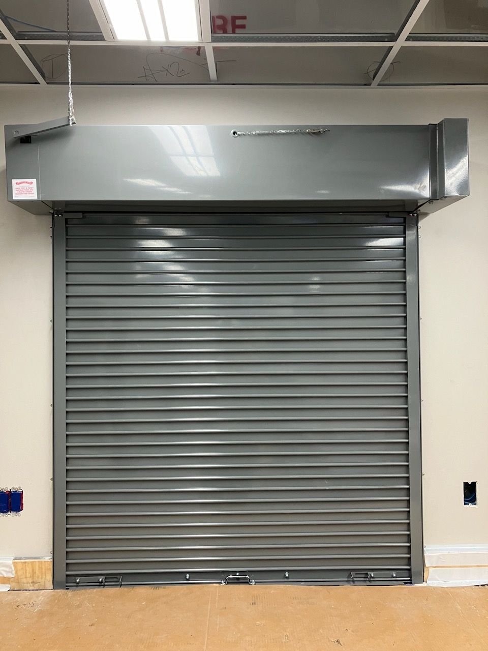A gray roller shutter door is closed in a room.