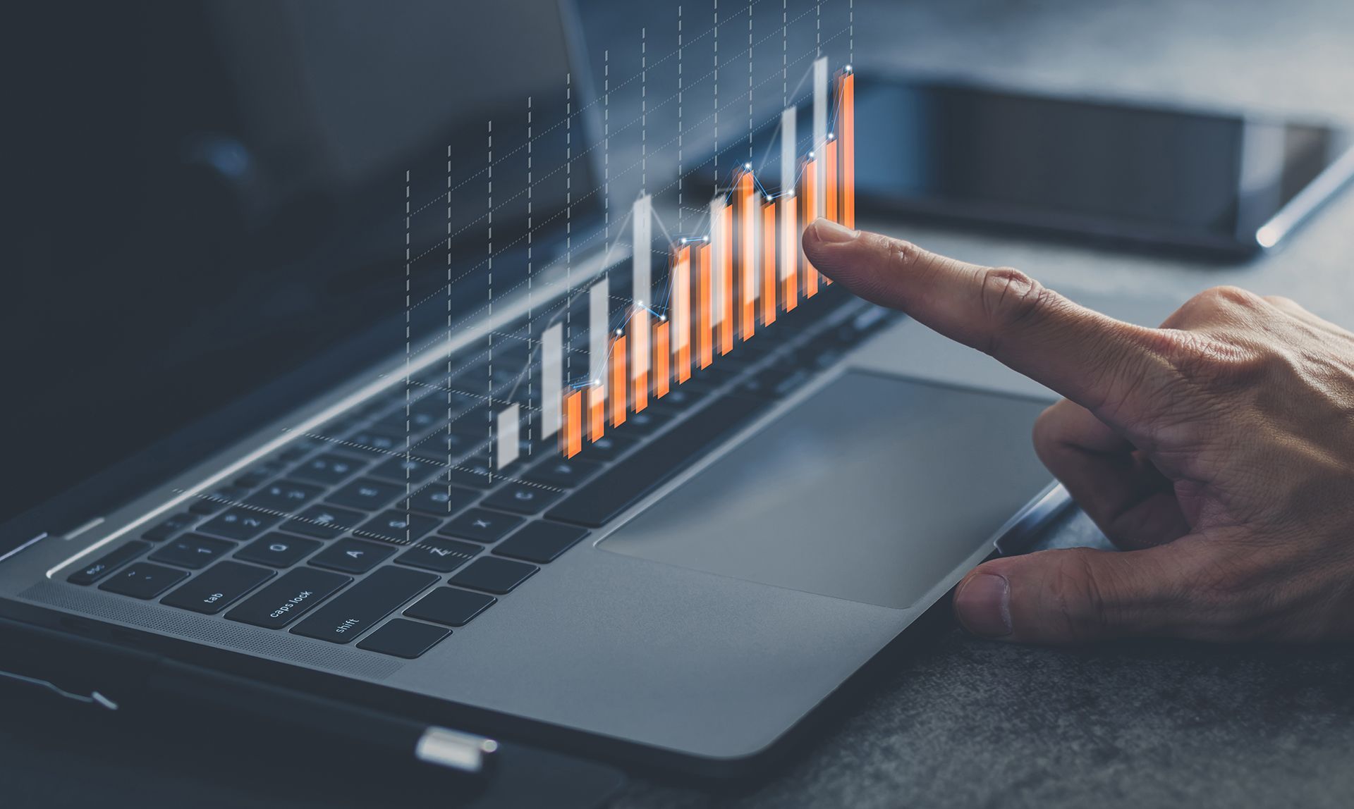 A person is pointing at a graph on a laptop computer.