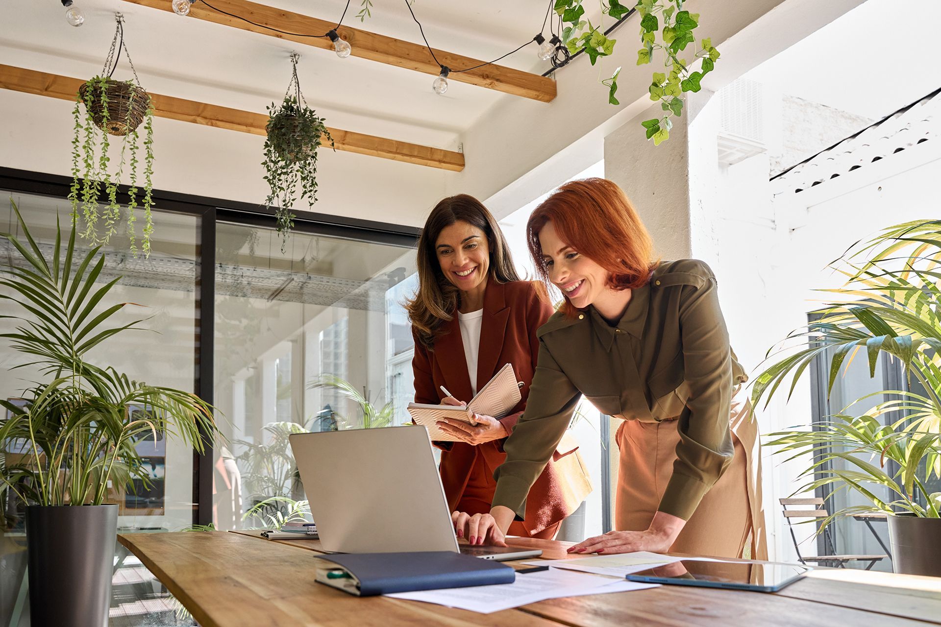 Two women are looking at a laptop computer in an office.