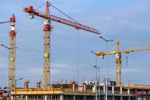 A group of construction cranes are working on a building under construction.