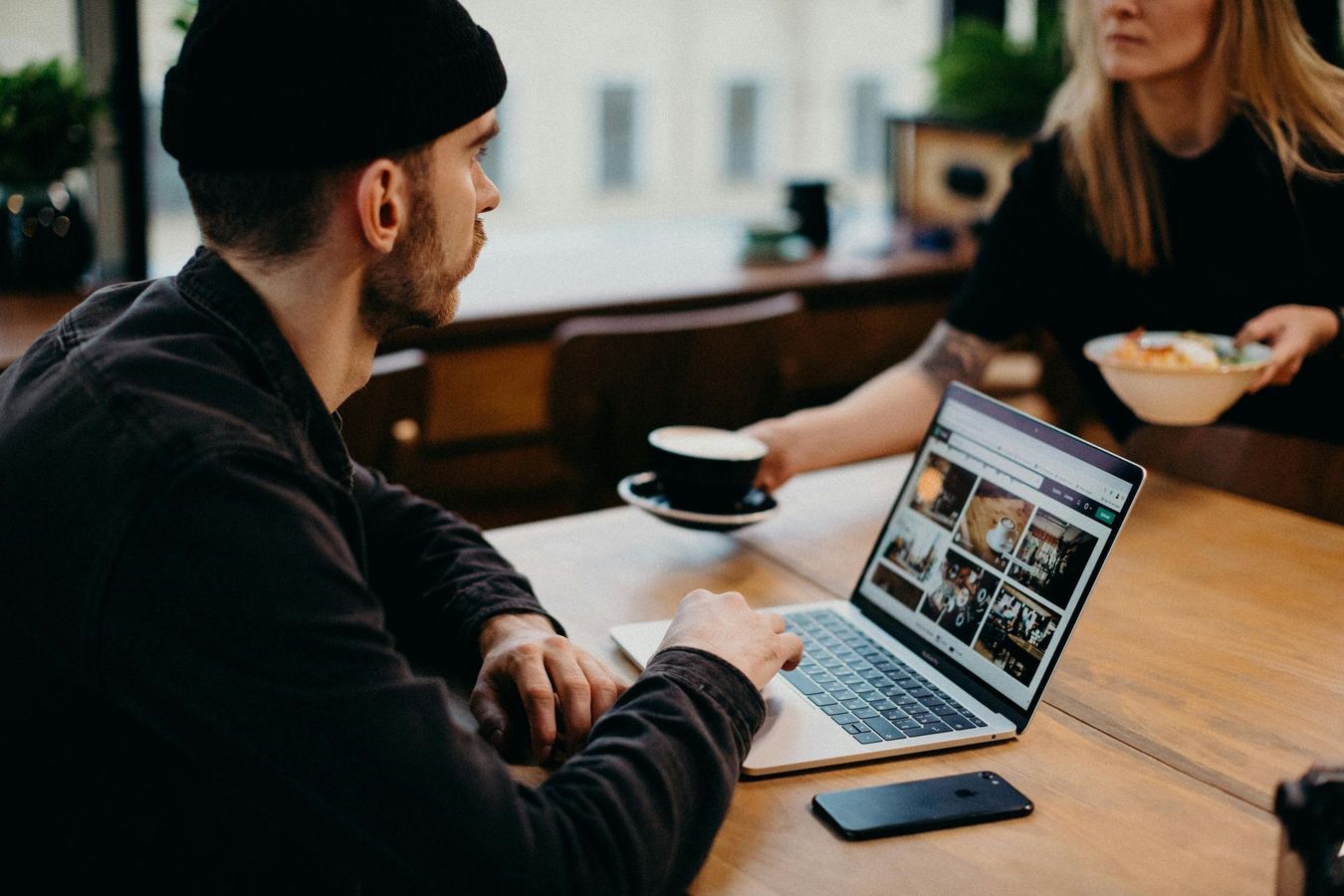 A man is sitting at a table with a laptop and a cup of coffee.