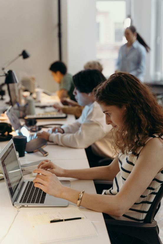 A woman is sitting at a desk using a laptop computer.