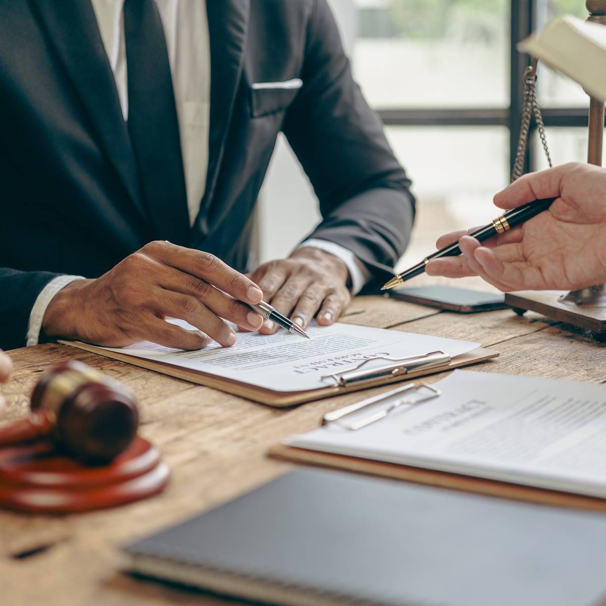 Notebook with pen and laptop on a dark desk.