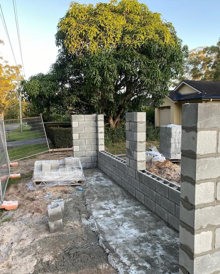 A Brick Wall Is Being Built In Front Of A House — Millers Masonry In Port Macquarie, NSW