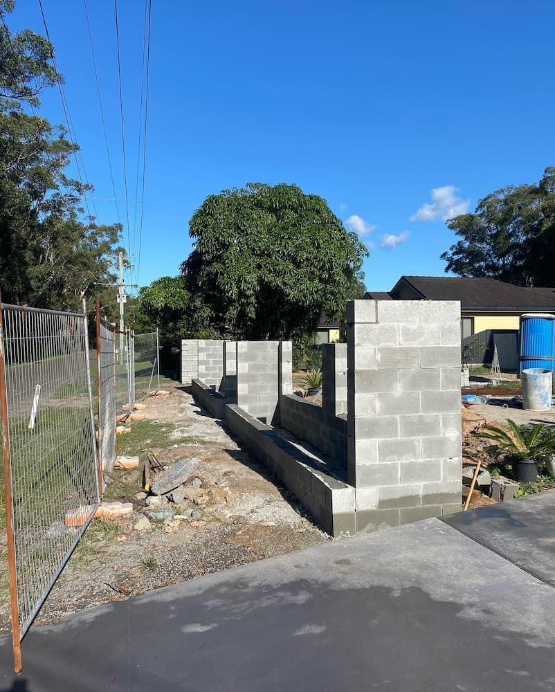A Brick Wall Is Being Built In Front Of A House — Millers Masonry In Port Macquarie, NSW