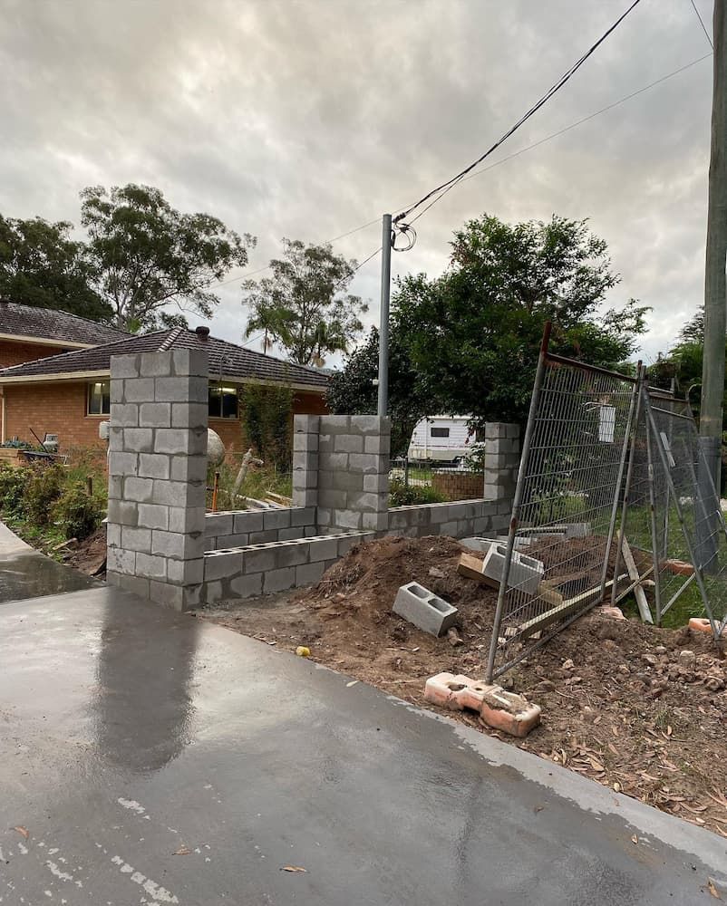 A Brick Wall Is Being Built In Front Of A House — Millers Masonry In Port Macquarie, NSW