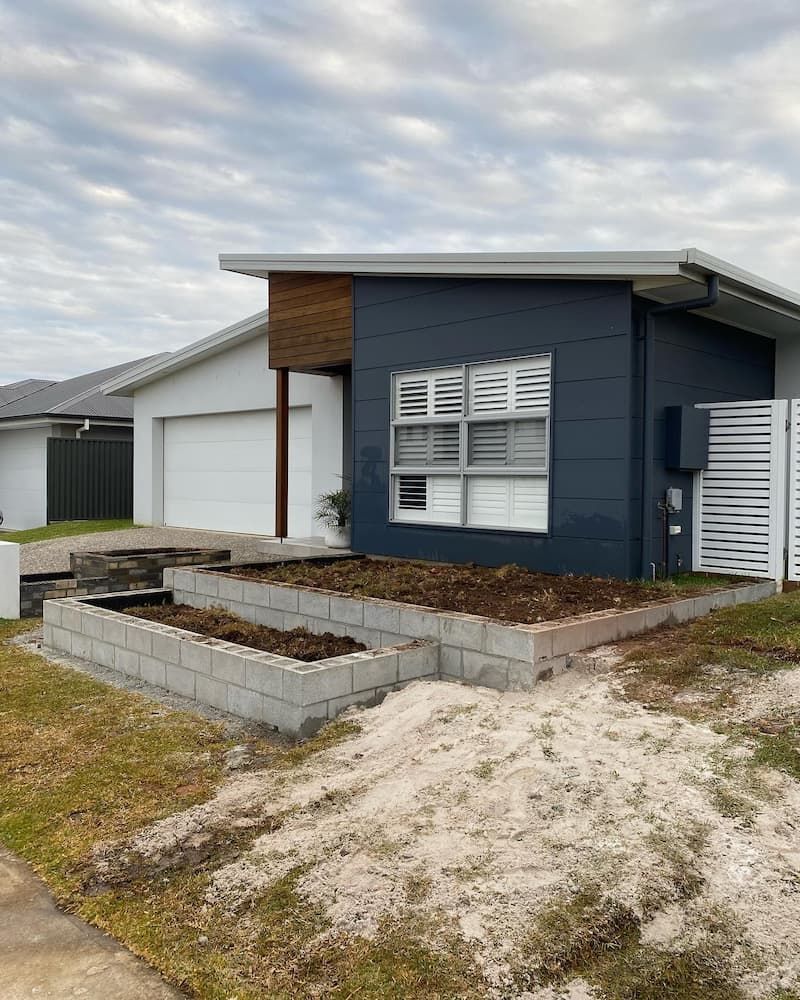 A Blue And White House With A Fence In Front Of It — Millers Masonry In Laurieton, NSW
