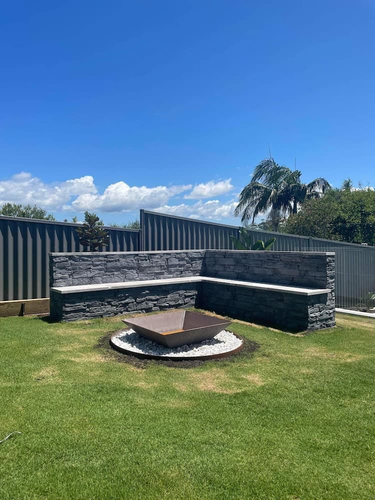 There Is A Fire Pit In The Middle Of The Grass In The Backyard — Millers Masonry In Laurieton, NSW