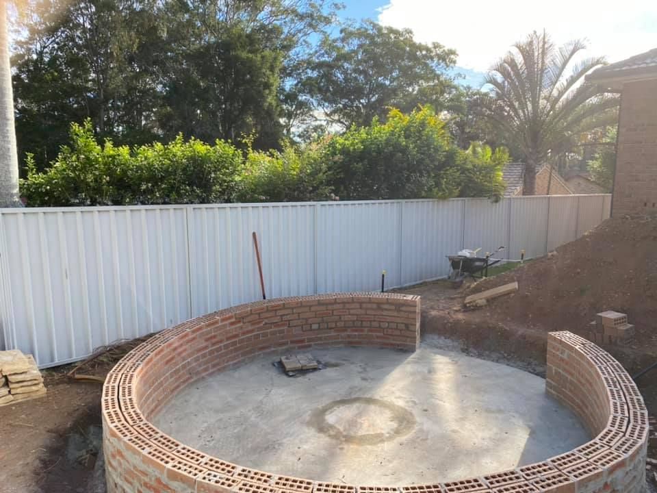 A Circular Brick Wall Is Being Built In A Backyard — Millers Masonry In Port Macquarie, NSW