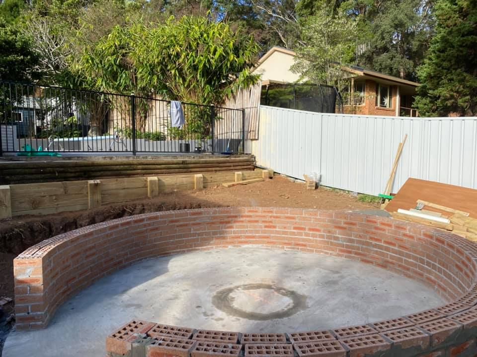 A Circular Brick Wall Is Being Built In A Backyard — Millers Masonry In Port Macquarie, NSW