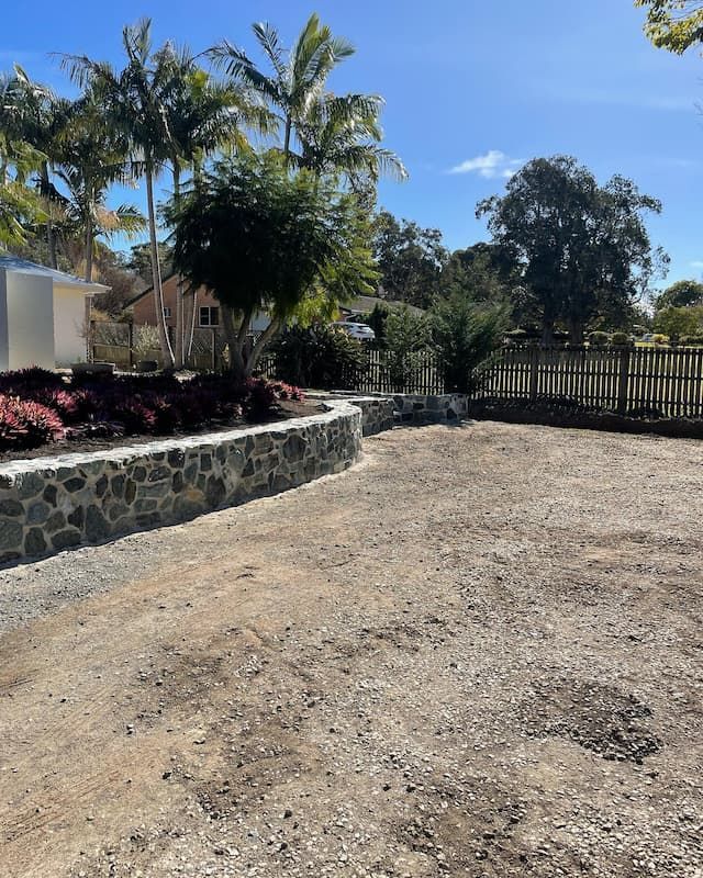 A Dirt Road With A Stone Wall And Trees In The Background — Millers Masonry In Port Macquarie, NSW
