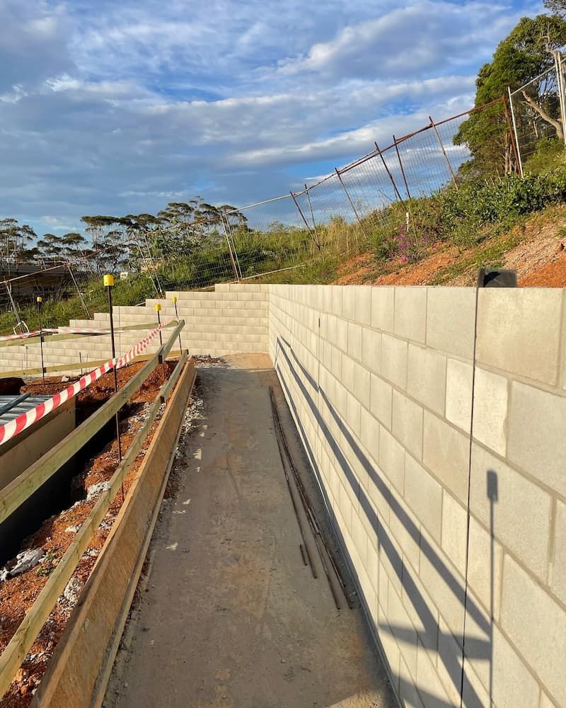 A Brick Wall Is Being Built On A Hillside — Millers Masonry In Port Macquarie, NSW