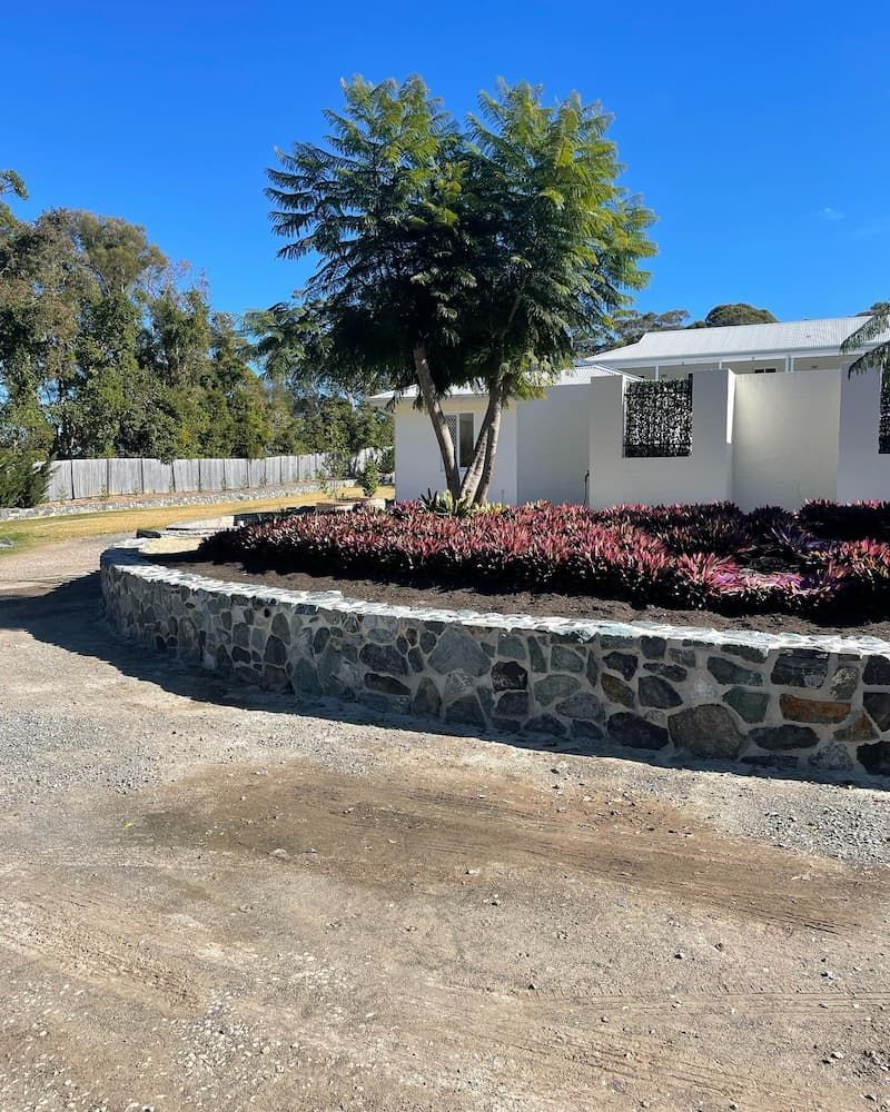 A White House With A Stone Wall And Flowers In Front Of It — Millers Masonry In Port Macquarie, NSW
