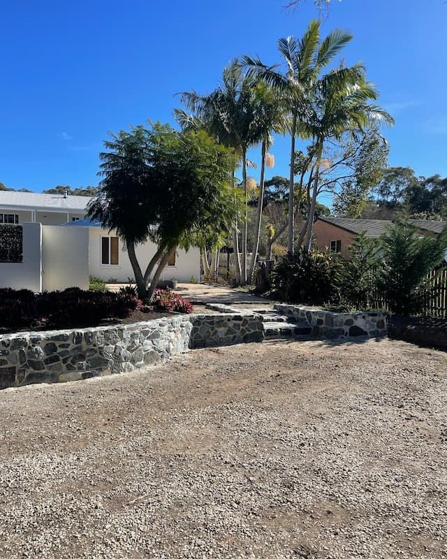 A Driveway Leading To A House With Palm Trees In The Background — Millers Masonry In Port Macquarie, NSW
