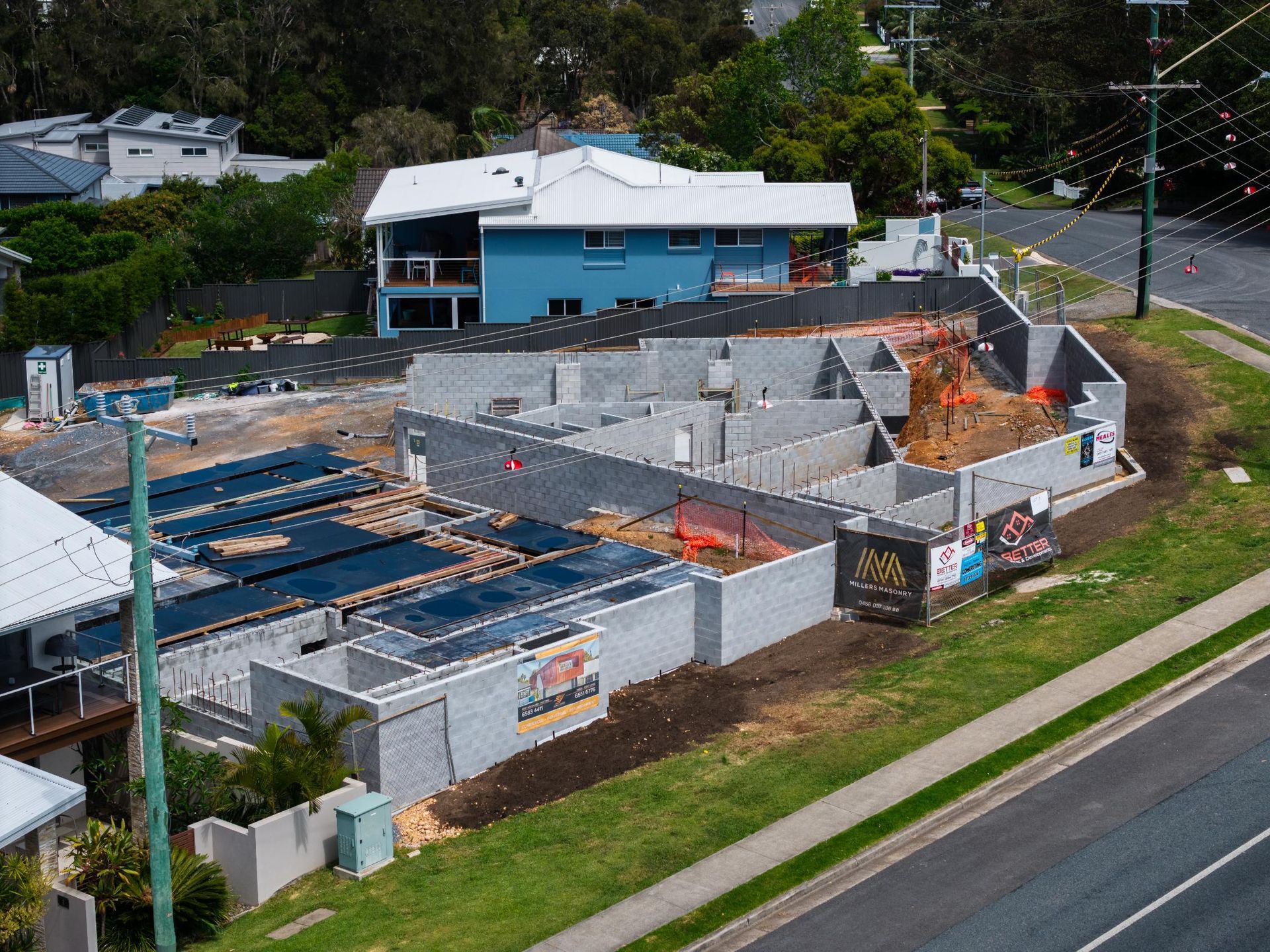 Construction Site with Gray Block Walls, a Blue House — Millers Masonry In Port Macquarie, NSW