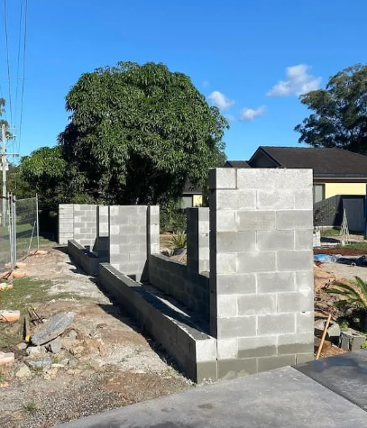 A Brick Wall Is Being Built In Front Of A House — Millers Masonry In Port Macquarie, NSW