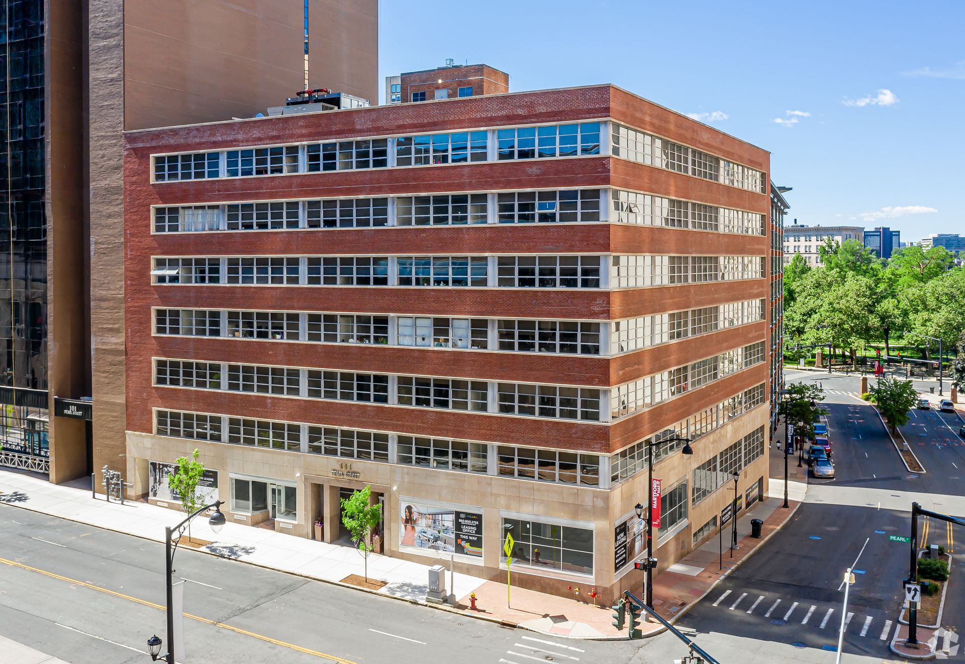 An aerial view of a large brick building on the corner of a city street.