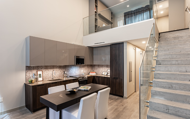 A kitchen with a table and chairs and stairs leading to the second floor.
