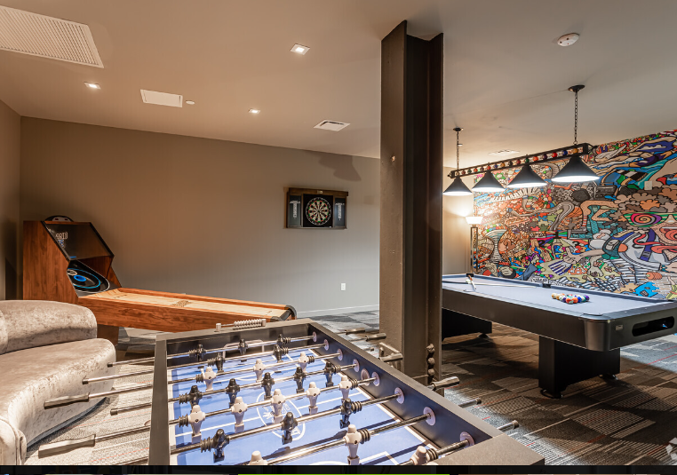 A game room with a pool table , foosball table , and a couch.